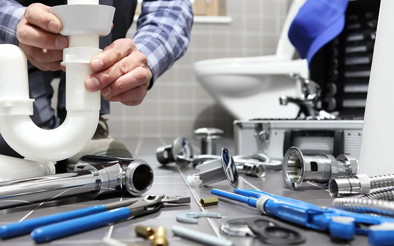 Technician performing professional plumbing service to repair a kitchen sink and ensure proper water flow.