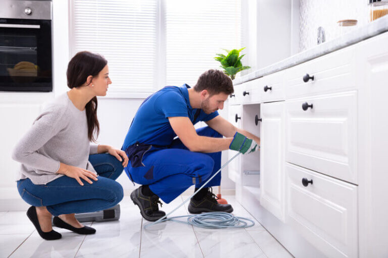 Technician performing water heater repair, fixing a leaking pipe with tools in a utility room.
